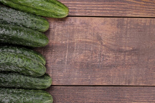 Verse groene ingelijste komkommers op een bruine houten tafel met ruimte voor een inscriptie