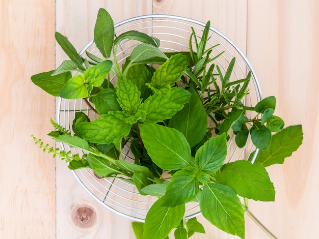 Verse groene kruiden in de mand op houten achtergrond.