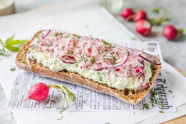 Verse groene lente sandwich met roomkaas en radijs op lichte achtergrond. Copyspace