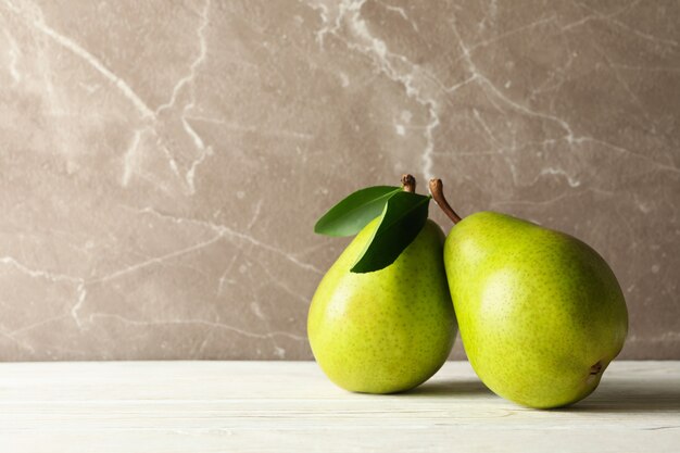 Verse groene peren op houten tafel tegen een grijze achtergrond