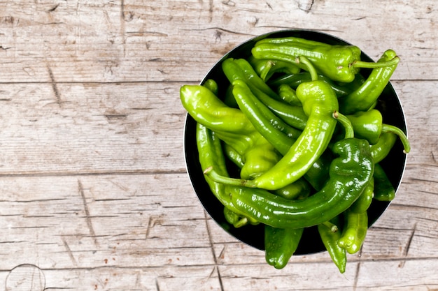 Verse groene ruwe peper in metaalkom op rustieke houten lijstachtergrond.