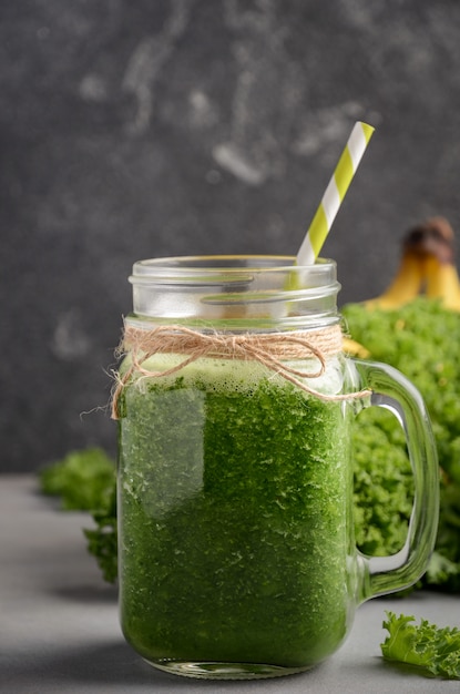 Verse groene smoothie met boerenkool en banaan in een pot.