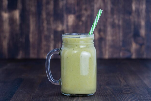 Verse groene smoothie van avocado-kiwi-banaan en honing in glazen mok op houten achtergrond close-up Concept van gezond eten