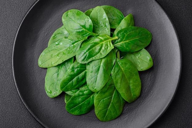 Verse groene spinazieblaadjes op een zwarte keramische plaat