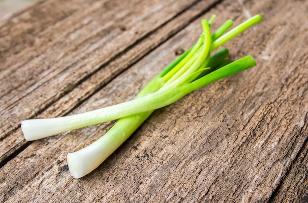 Verse groene uien op oude houten achtergrond