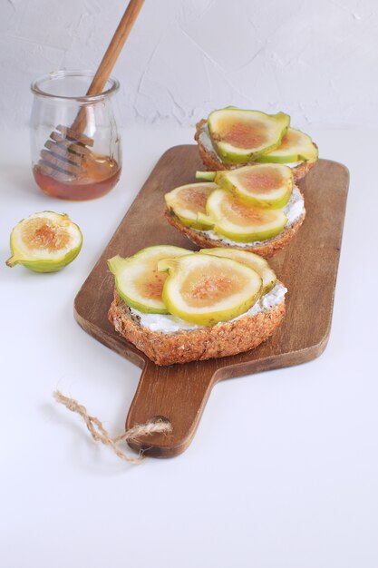 Verse groene vijgen Houten snijplank Volkorenbrood Honing Geitenkaas