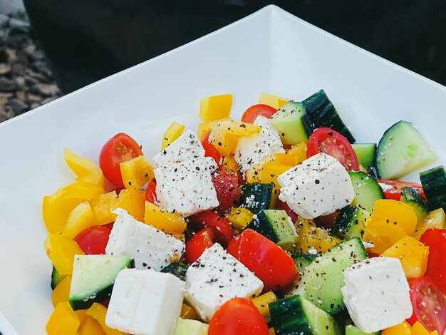 Verse groente Griekse salade met kerstomaatjes, paprika, komkommer, fetakaas, olijfolie en seizoenskruiden, gezond voedingsdieet en heerlijk maaltijdrecept