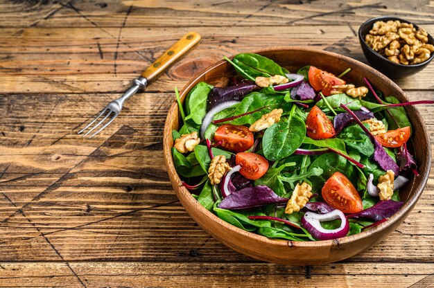 Verse groente groene salade met bladeren mangold, snijbiet, spinazie, rucola en noten. houten achtergrond. bovenaanzicht. ruimte kopiëren.