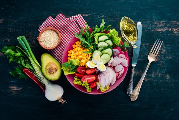 Verse Groente Salade. Maïs, radijs, ui, komkommer, kwarteleitjes. Op een houten achtergrond. Bovenaanzicht. Gratis exemplaar ruimte.