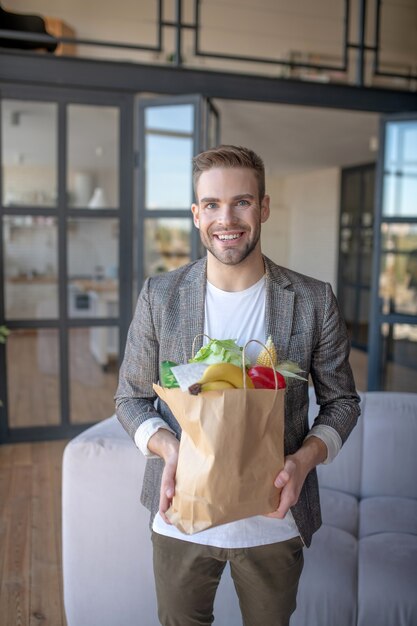 Verse groenten. Een lachende jonge man met een pakje groenten