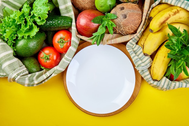 Verse groenten en fruit in eco katoenen zakken rond plaat op tafel