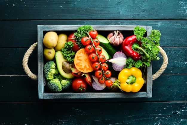 Verse groenten en fruit in een houten kist. Avocado's, tomaten, aardbeien, meloenen, aardappelen, paprika, citrus. Bovenaanzicht. Vrije ruimte voor uw tekst.