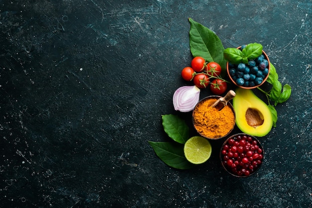 Verse groenten en fruit: venkel, avocado, granaatappel, bessen, kool en basilicum. biologisch gezond veganistisch eten. op een zwarte stenen achtergrond.