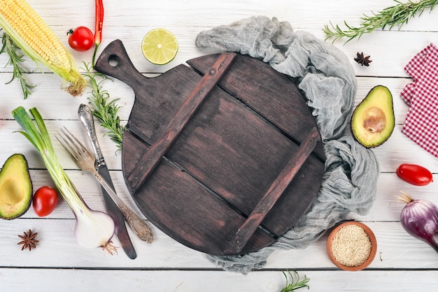 Verse groenten en ingrediënten voor het koken rond vintage snijplank op rustieke achtergrond bovenaanzicht plaats voor tekst Veganistisch eten vegetarisch en gezond koken concept