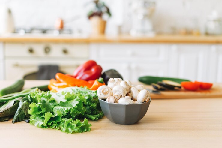 Verse groenten, groene salade, paprika, champignons en aubergine op het kookproces van de keukentafel
