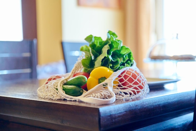 Verse groenten in een mesh eco-tas op tafel in de keuken