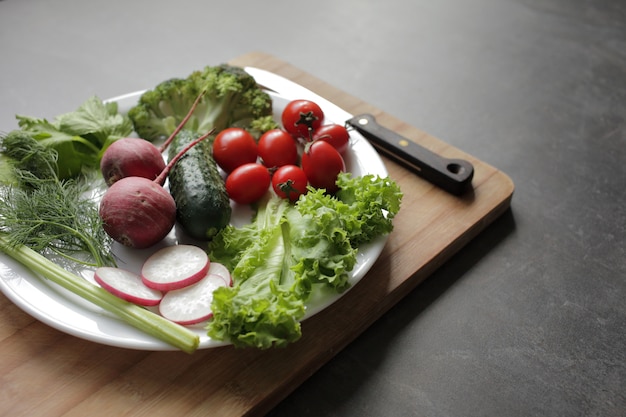 Verse groenten in een witte plaat op een grijze tafel