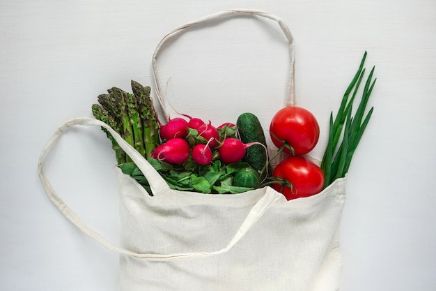 Verse groenten in mesh boodschappentas geïsoleerd op de witte tafel. Milieuvriendelijk. Stop plastic, red de planeet.