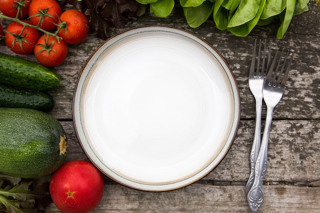 Verse groenten voor het smakelijke veganist en dieet koken of salade die rond lege plaat op rustieke houten achtergrond, hoogste mening maken