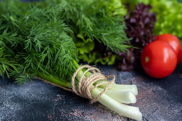 Verse groenten voor salade Tomaten en slakomkommers met courgette en kool met dille De voordelen van de lenteoogst en vitaminen Op een donkere achtergrondkopieerruimte