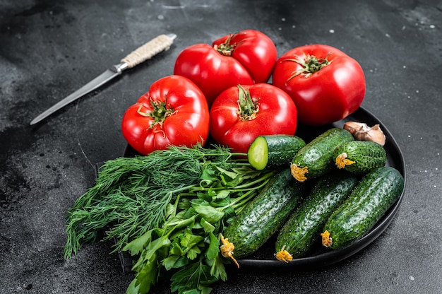 Verse groenten voor zomer groene salade, rode tomaten, komkommers, peterselie, kruiden. Zwarte achtergrond. Bovenaanzicht.