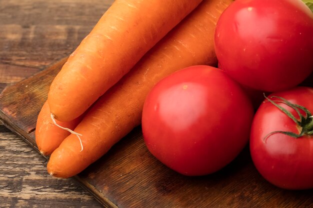 Verse groenten, wortelen en tomaten op een snijplank ingrediënten voor het maken van gezonde gerechten