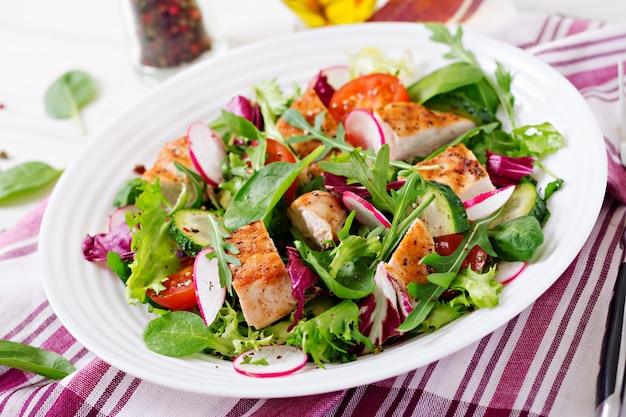 Verse groentesalade met gegrilde kipfilet - tomaten, komkommers, radijs en meng slablaadjes. Kip salade. Gezond eten.