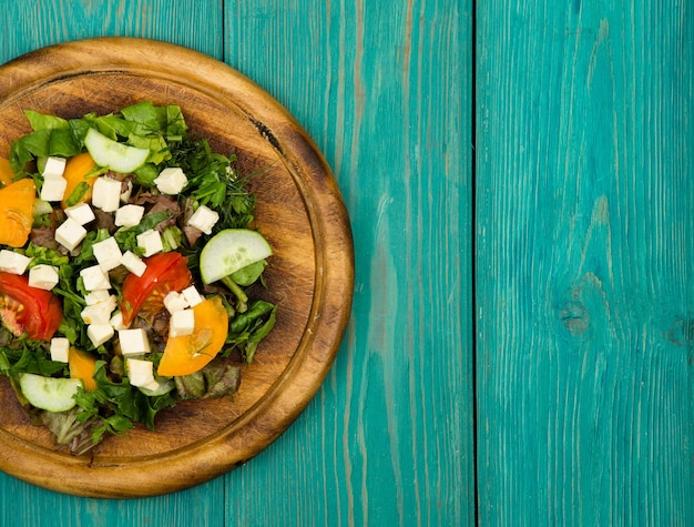 Verse groentesalade met groene kaastomatenkomkommer op een blauwe houten tafel