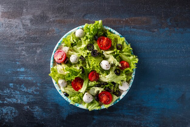 Verse groentesalade met tomaten, kaas en olijven. Bovenaanzicht