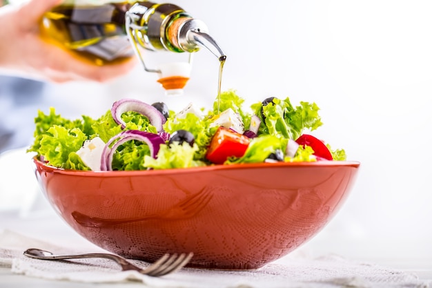 Verse groentesalade met tomatenuienkaas en olijven Olijfolie die in kom salade gieten