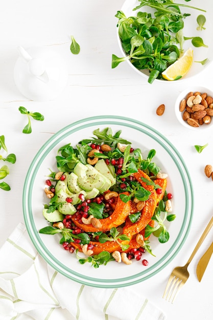 Verse groentesalade met veldsla gebakken flespompoen of pompoen avocado granaatappel cashewnoten en amandelnoten Gezond vegetarisch voedselconcept Bovenaanzicht