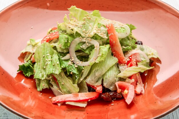 Verse groentesalade van Chinese kool, tomaat, peper en ui met olijf- of zonnebloemolie op houten tafel.