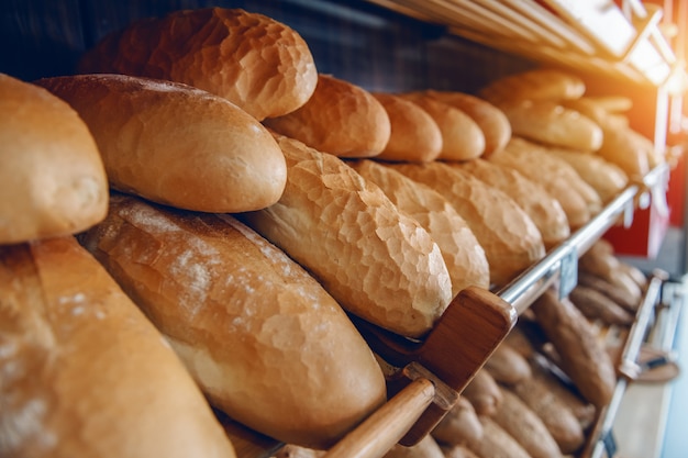 Verse heerlijke broden in rij op planken klaar voor verkoop. Bakkerij interieur.