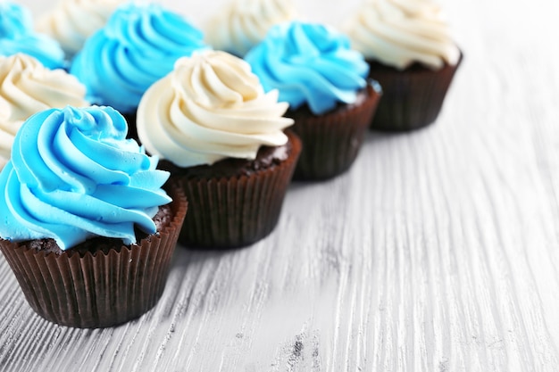 Verse heerlijke cupcakes in een rij op witte houten tafel