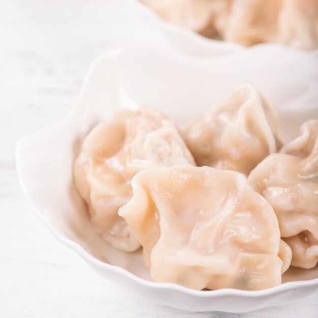 Verse, heerlijke gekookte varkensvlees gyoza dumplings, jiaozi op witte achtergrond met sojasaus en eetstokjes, close-up, levensstijl. zelfgemaakt ontwerpconcept.