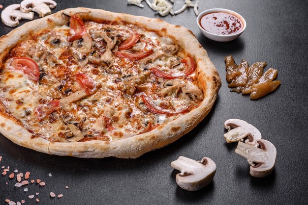 Verse heerlijke Italiaanse pizza met champignons en tomaten op een donkere betonnen ondergrond. Italiaanse keuken