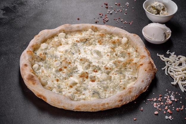 Verse heerlijke Italiaanse pizza met vier soorten kaas op een donkere betonnen ondergrond. Italiaanse keuken