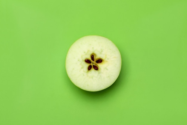 Verse helft van appel met zaad op groene achtergrond, bovenaanzicht.