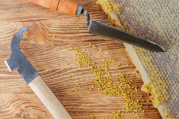 Verse honing in de kam en het gereedschap van de imker op een bruine houten tafel.