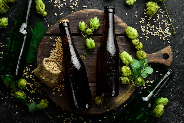 Verse hopglazen en bier Donker bier in glazen flessen op een zwarte stenen achtergrond Bierbanner