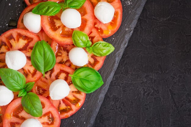 Verse Italiaanse caprese salade op donkere plaat. Bovenaanzicht met kopieerruimte