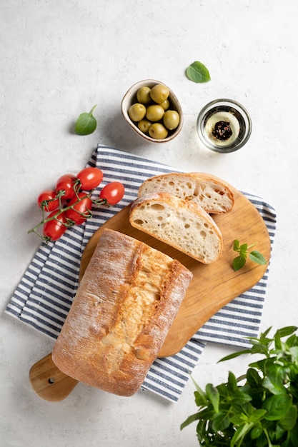 Verse italiaanse ciabatta brood gesneden plakjes met tomaat, basilicum en olijf op witte achtergrond. bovenaanzicht en kopieer ruimte.