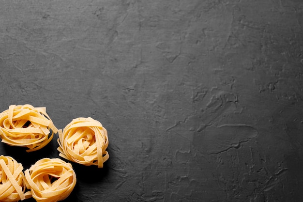 Verse italiaanse pasta l op een donkere achtergrond met kopie ruimte voor tekst. tagliatelle pastagenesten.