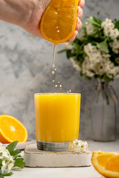 Verse jus d'orange in glas en vrouwelijke hand met een vers oranje fruit Spattend sinaasappelsap