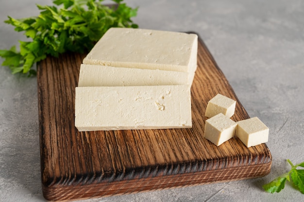 verse kaas tofu van sojabonen met peterselie op een houten snijplank