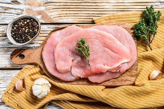 Verse kalkoen steaks met tijm en peper op snijplank. rauw biologisch pluimveevlees. bovenaanzicht