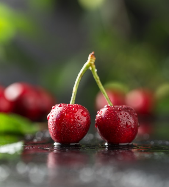 Verse kers met waterdruppels op donkere tafel.