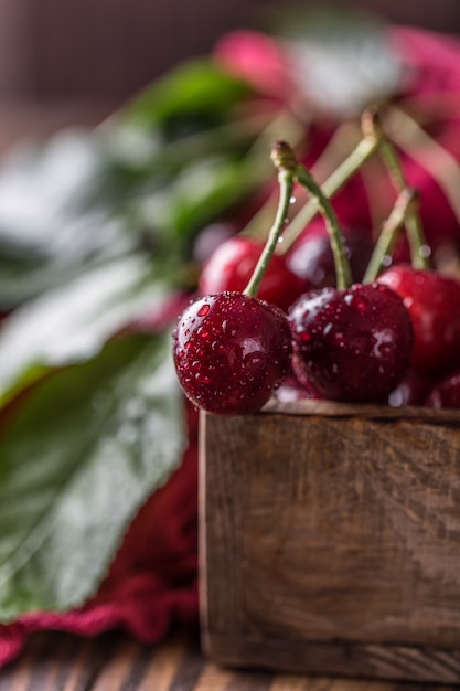 Verse kers met waterdruppels op rustieke houten tafel.