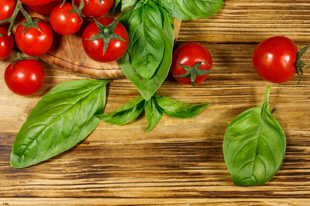 Verse kerstomaatjes met groene basilicumblaadjes op een houten tafel Bovenaanzicht