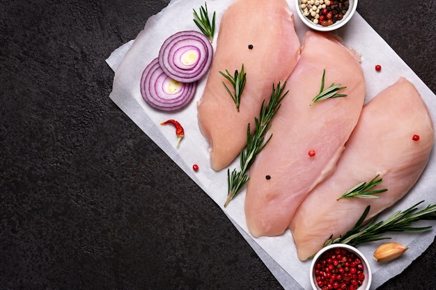 Verse kippenborstfilet met kruiden en specerijen op zwarte steenachtergrond Voorbereiding voor het koken